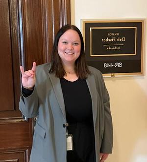 Faith Leiting standing in front of a door with a plaque that says Senator Deb Fischer, Nebraska..